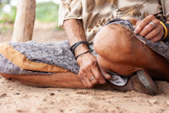 Elderly african Woman Sitting Cross Legged on Sand Close Up Detail of Hands and Skin Texture