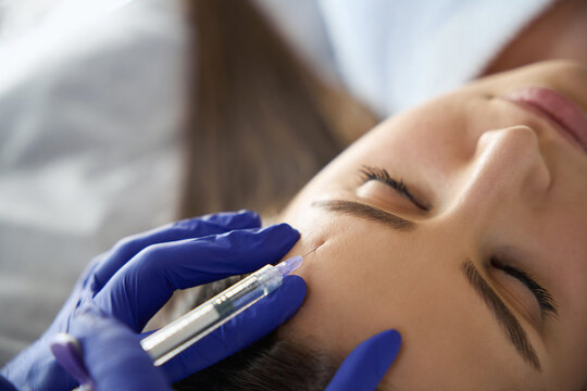 Close up of lady receiving injection in forehead zone at beauty salon