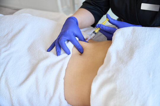 Doctor makes injection of ozone gas in female abdomen on side on ozone therapy