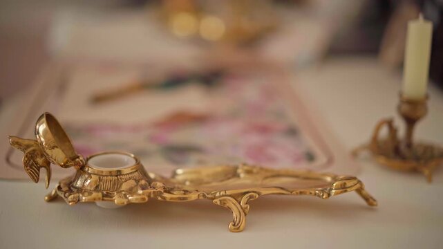 Victorian-style gold inkwell with bird figurine on ornate desk, suitable for historical decoration concepts or antique collections. Fingers open vintage rococo inkwell. Pen Pals, handwritten letter