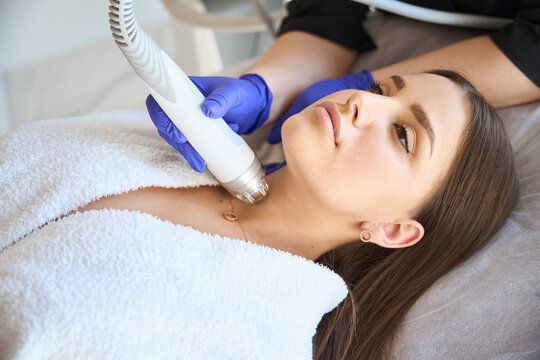 Cosmetologist making RF lifting procedure for young woman