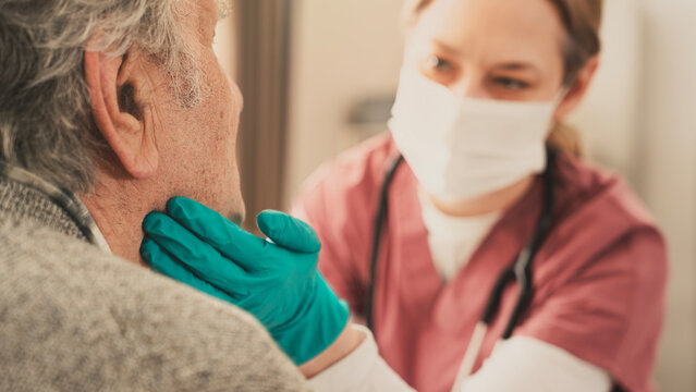 The doctor examines an old man with a sore throat