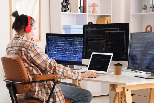 Female programmer with headphones working at desk in office