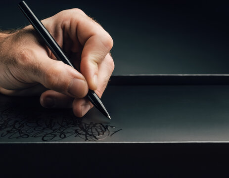 Close up of human hand writing handwritten scribble with pen. luxury package conveys sense of personal sincerity on sleek black surface, an elegant gesture