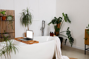 Interior of light bathroom with green plants and bathtub © Pixel-Shot