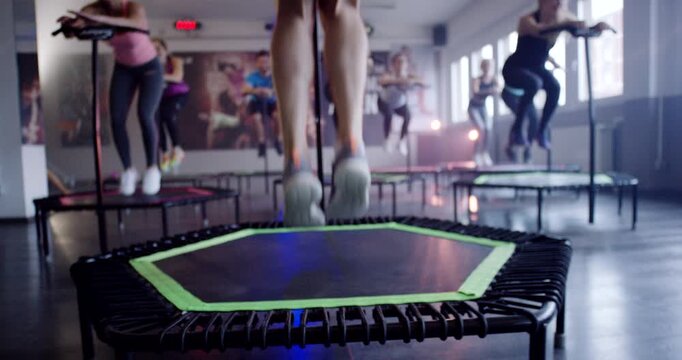 Low angle view of person jumping on mini trampoline during workout in fitness center