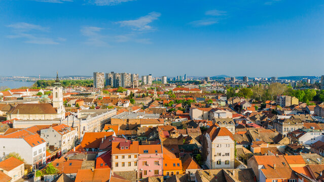 Aerial view of the historic Zemun district featuring red-tiled rooftops, the St. Nicholas Church tower, and the modern city skyline under a clear blue sky in Belgrade, City of Belgrade, Serbia.