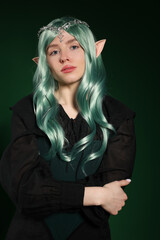 Naklejka premium Beautiful girl dressed as elf on dark green background