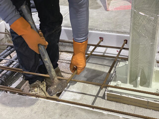 Worker using a hammer to install anchor steel for a steel column foundation. © WATCHARAPHON