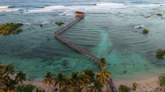 Cinematic aerial shot of the iconic wooden boardwalk at Cloud 9, General Luna, Siargao. Drone footage showing the tropical turquoise lagoon and the famous surf pier in the Philippines