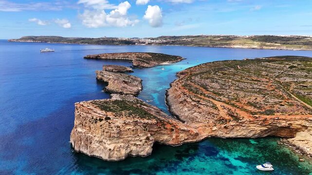 Blue Lagoon in Comino Għajnsielem Gozo Region Malta with limestone cliffs and garigue vegetation including Thymbra capitata and Euphorbia dendroides habitat over clear Mediterranean water, aerial