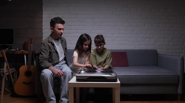 Father and children gathering around a turntable, listening to music and introducing kids to classic sounds of vinyl records during a cozy evening at home