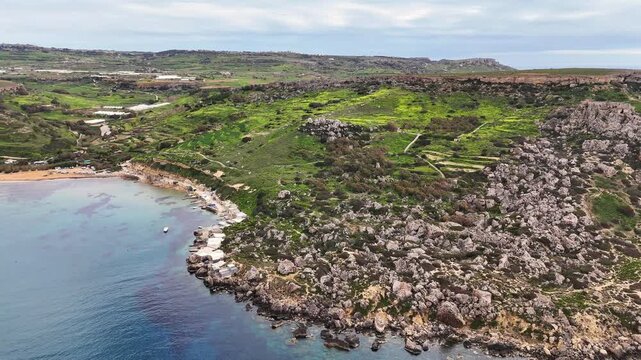 Qarraba Bay Mellieħa Malta with rocky shoreline formed by globigerina limestone and clay slopes with Mediterranean garigue biome vegetation overlooking sheltered bay along Mediterranean sea, panning