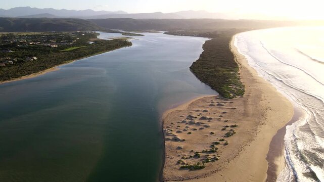 Aerial pullback over Keurbooms River estuary mouth at sunrise in Plettenberg Bay