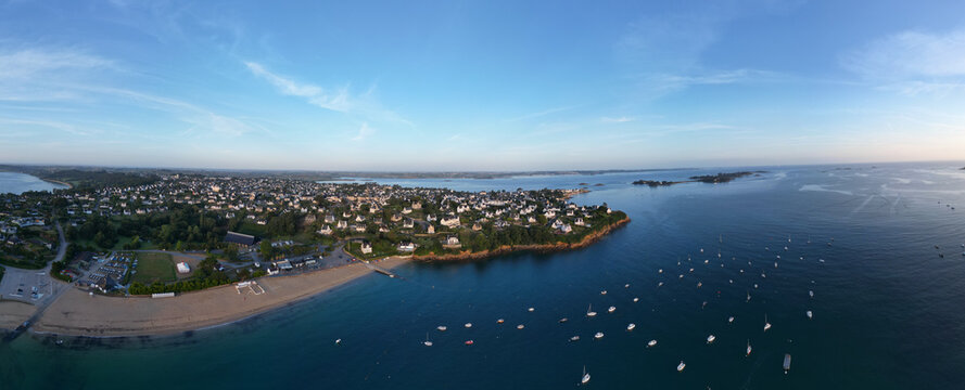 Aerial view of Carantec's golden beach, green headland with white houses, and a deep blue bay sparkling with boats, Carantec, Bretagne, France.