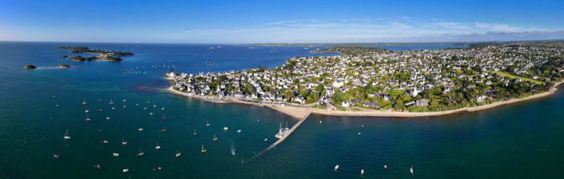 Aerial view of boats bobbing in the turquoise water, a pier stretching out from the sandy beach, Carantec, France.
