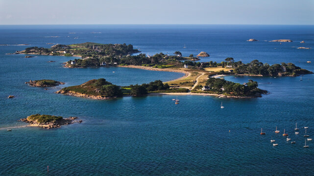 Aerial view of Callot island with sandy beaches and scattered houses, where the deep blue sea meets the shore, Carantec, France.