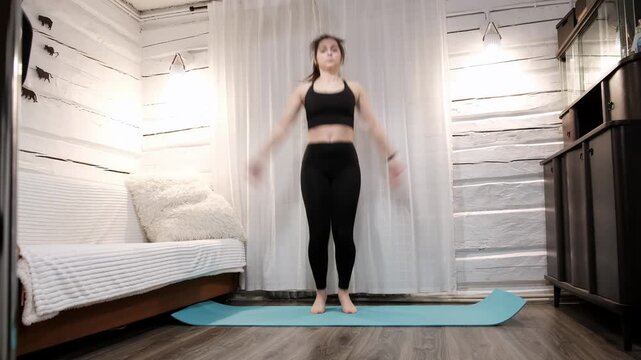 Caucasian woman doing an exercise Jumping Jacks on floor at home. Fast workout. Morning warmup. Person strengthening the muscles of legs, endurance and balance. Strong sporty body. HQ 4k footage.