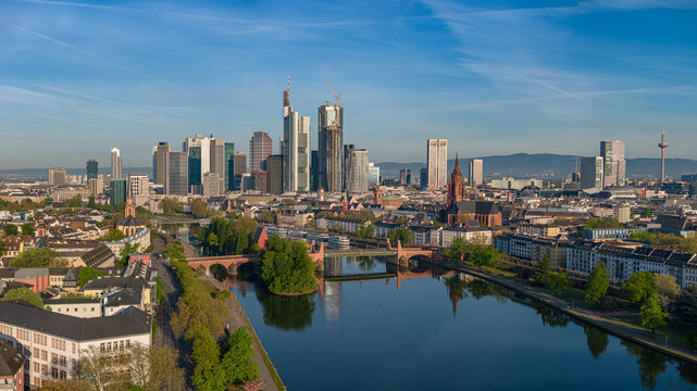 Aerial view of the majestic Frankfurt skyline, with its gleaming skyscrapers rising above the serene Main River and its historic bridges, Frankfurt am Main, Hessen, Germany.