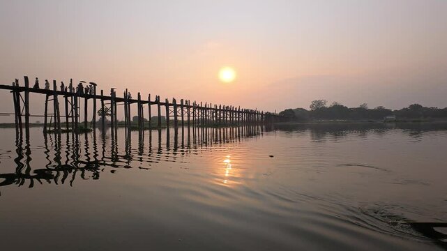 Silhouette and reflection on the water of U Bein Bridge at Sunset in Mandalay, Myanmar