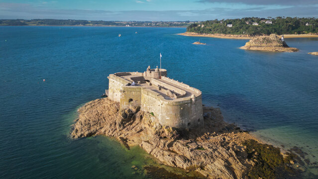 Aerial view of the ancient Chateau du Taureau fort standing majestically on rugged brown rocks amidst the deep blue sea, Plouezoc'h, Bretagne, France.