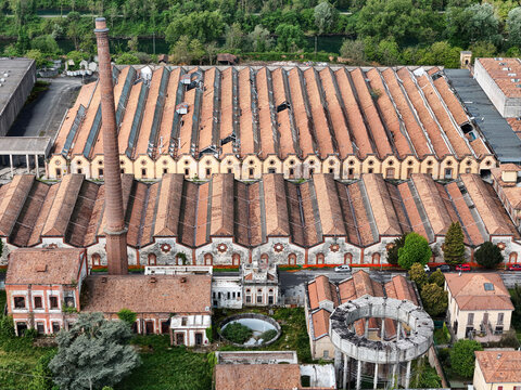 Aerial view of the historic Industrial Village of Crespi d'Adda featuring saw-tooth factory roofs and a tall brick chimney in Capriate San Gervasio, Lombardia, Italy.