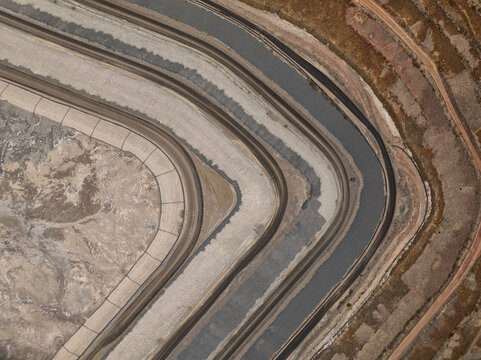 Aerial view of curving terraces and a winding dark channel, revealing contrasting earthy tones, Tucson, Arizona, United States.
