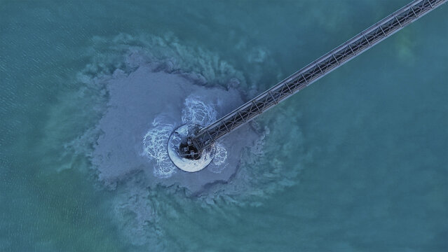 Aerial view of an industrial discharge creating a swirling plume of murky sediment in vibrant turquoise waters, Tucson, Arizona, United States.