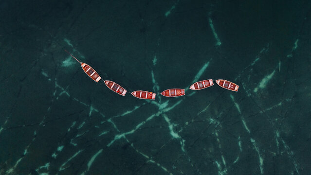 Aerial view of wooden boats forming a gentle arc on the deep emerald waters of Lago di Braies, Lago di Braies, Trentino-South Tyrol, Italy.