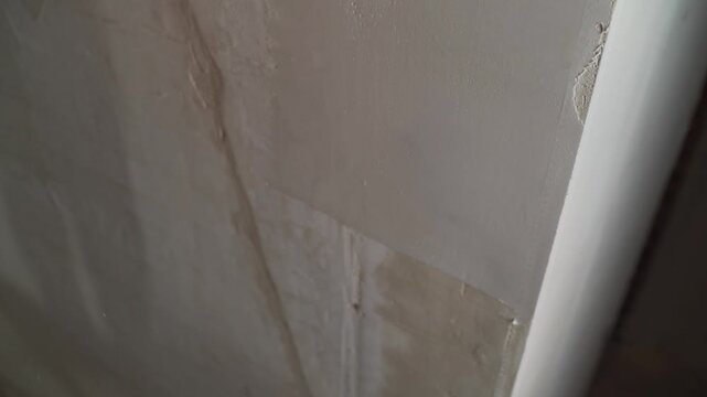 Close up of worker applying plaster or putty to wall with spatula. Professional plasterer smoothing drywall for home renovation or construction. Finishing and repair work