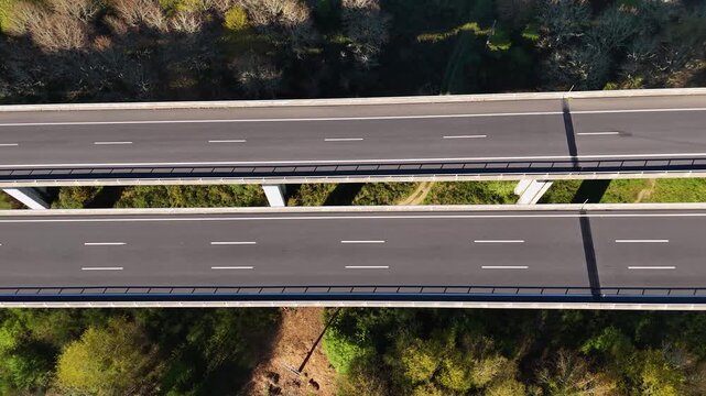Aerial view of Viaducto Arnoia bridge with a car driving over lush green forest in Allariz, Province of Ourense, Spain.