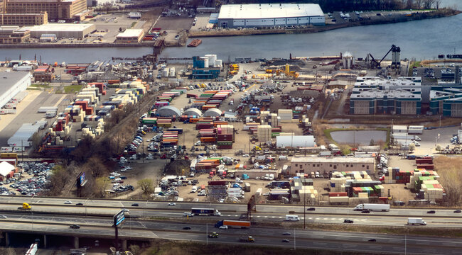 Aerial view of a sprawling industrial port, a mosaic of containers beside a dark river and a bustling highway, Elizabeth, New Jersey, United States.