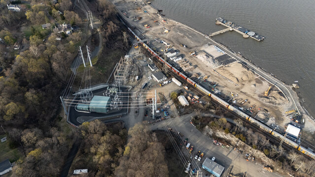 Aerial view of a train beside the Hudson River, with electrical towers casting long shadows near Tomkins Cove, Stony Point, New York, United States.