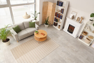 Obraz premium Shelving units with books, fireplace, sofa and coffee table in interior of stylish living room