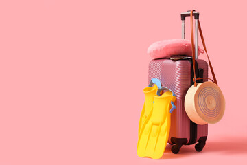 Suitcase with snorkeling flippers, travel pillow and bag on pink background © Pixel-Shot