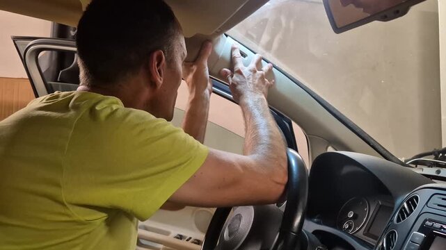 Car repair, man, interior, adjusting A-pillar trim panel, performing automotive maintenance work.