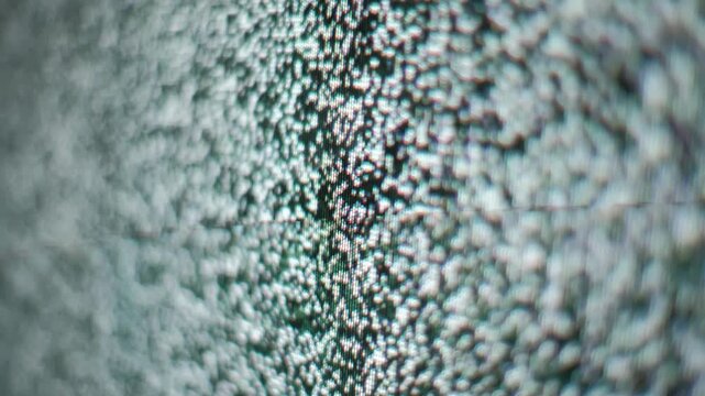 Angled close-up perspective shows dynamic flickering static on a television display. The white and black pixels create a fuzzy noise pattern indicating signal interference.