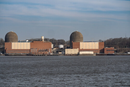 Aerial view of the Indian Point Energy Center's structures standing firmly along the Hudson River's edge, a contrast of industrial might against the serene water, Peekskill, New York, United States.