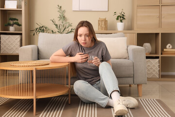 Obraz premium Emotional young woman with glass of water having panic attack at home