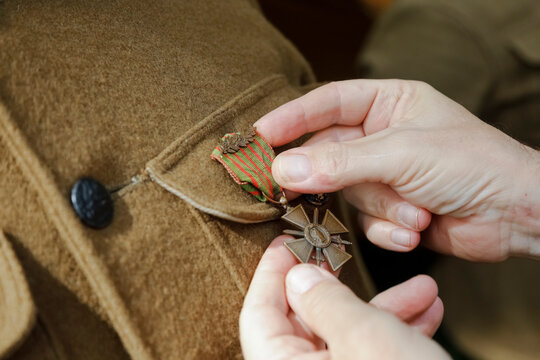 Hands pinning medal onto World War I military uniform