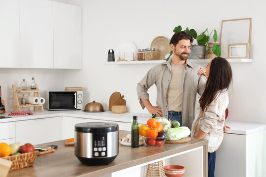 Young couple with multi cooker on table in kitchen