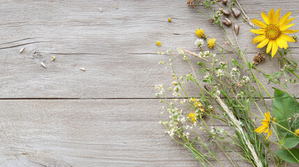 Obraz premium Collection of wildflowers and sunflower arranged on rustic wooden surface, showcasing nature beauty and simplicity