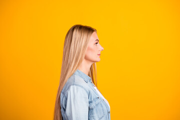 Side-profile portrait of a confident blonde woman against a bright yellow background, casual denim shirt and long hair conveying optimism and modern lifestyle © deagreez