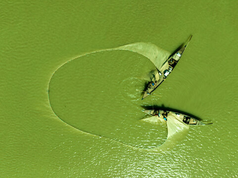 Aerial view of two boats and their nets forming a striking, light pattern against the deep, green river, Bogura, Rajshahi Division, Bangladesh.