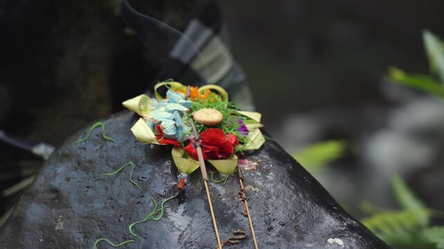 Balinese Offering with Incense Beside Flowing Jungle River