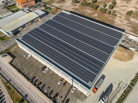Aerial view of a vast, gleaming array of solar panels covering a modern industrial building, contrasting with the earthy tones of its surroundings, Vagos, Aveiro, Portugal.