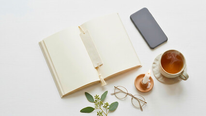 Fototapeta premium Digital detox flat lay with phone face down, book and tea on white background