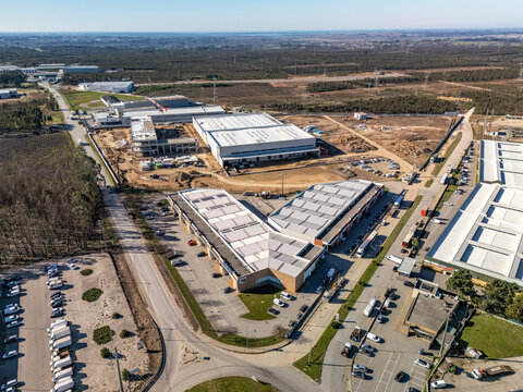 Aerial view of an industrial park with bright buildings and construction, bordered by dense forest, Albergaria-a-Velha, Aveiro District, Portugal.