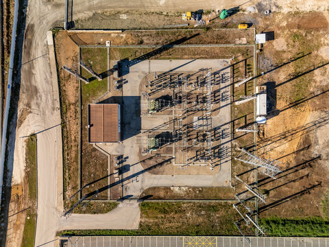 Aerial view of a sprawling electrical substation with intricate power lines casting long shadows across the dry earth, Albergaria-a-Velha, Aveiro District, Portugal.