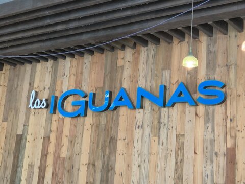 London UK 07.07.2025 las iguanas restaurant sign with blue lettering on wooden wall tropical style branding exterior detail in urban dining environment